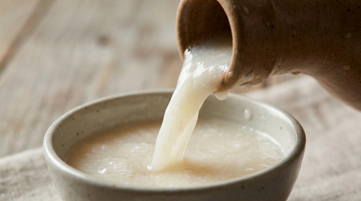 Close-up of makgeolli being poured, showing its cloudy tangy-sweet fermented rice wine texture